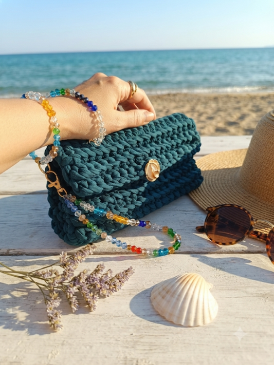 Pochette Ottanio in maglina all'uncinetto con bracciale in cristalli austriaci multicolor sulla sabbia in riva al mare