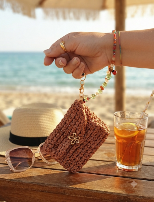 Mini Pochette Rame tenuta per il bracciale porta-pochette in cristalli multicolor su tavolo da spiaggia con cappello, occhiali e bibita